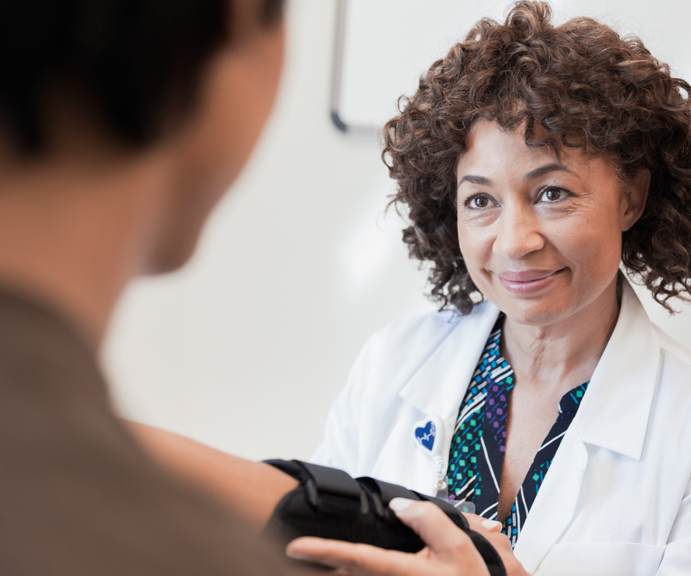 A smiling physician in a white lab coat examines a patient.